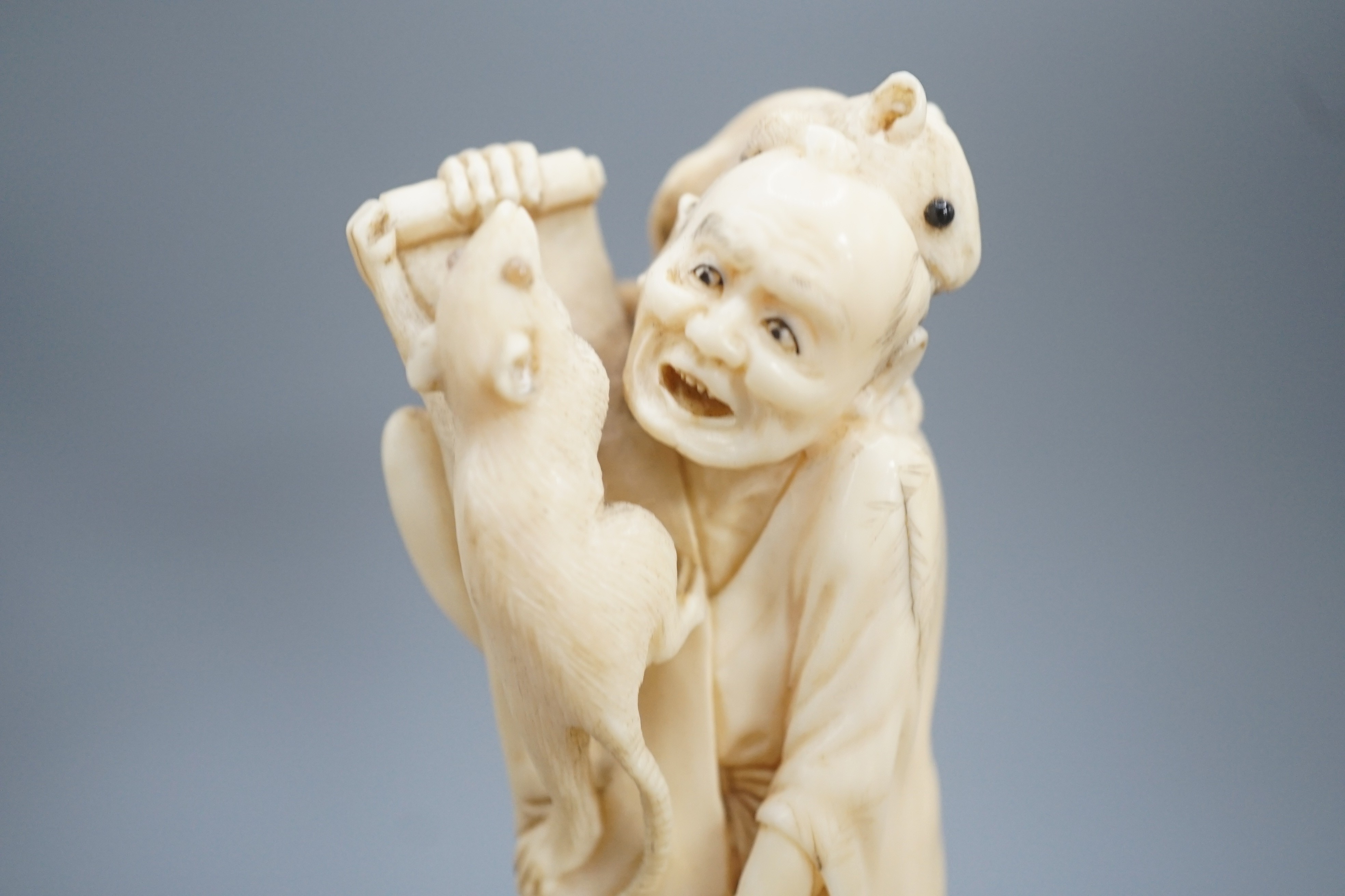 A Japanese ivory okimono of a man with giant rats clambering over him, signed, late 19th century 12.5cm, wood stand